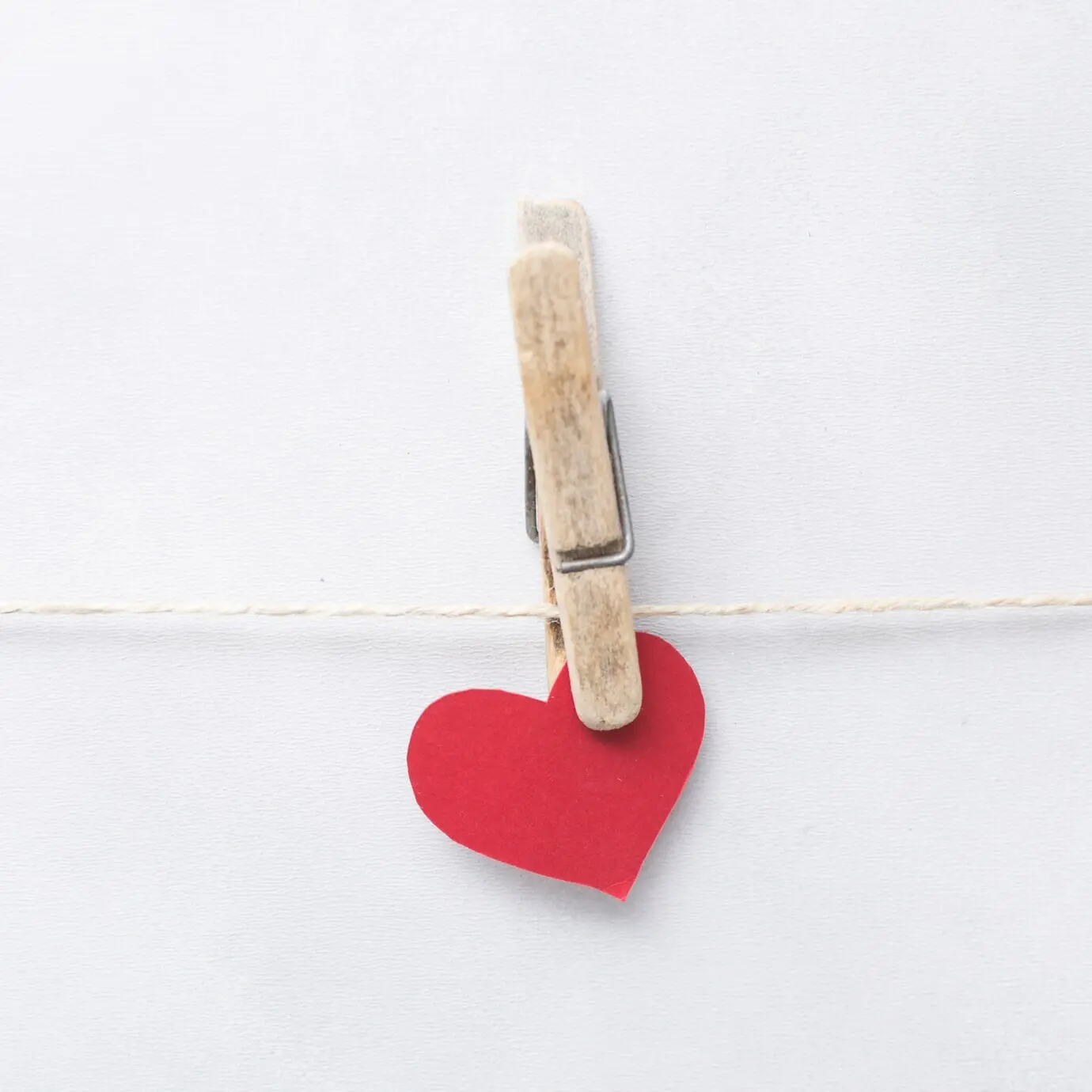 Herzornament mit Nadel, das an einem Faden hängt.